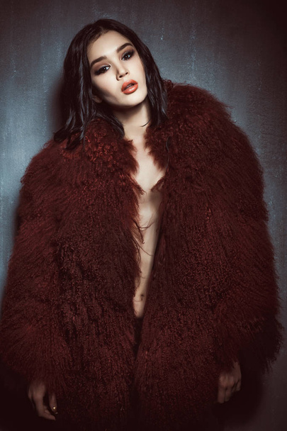joven hermosa chica en el gran abrigo rojo y esponjoso está de pie
  - Foto, Imagen