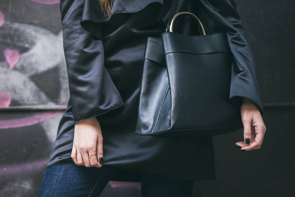détails parfaits tenue d'automne. femme élégante portant de la soie noire sur la robe d'épaule et sac à main noir à la mode
. - Photo, image