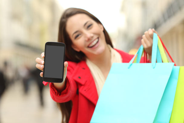 Shopper with shopping bags showing phone - Zdjęcie, obraz
