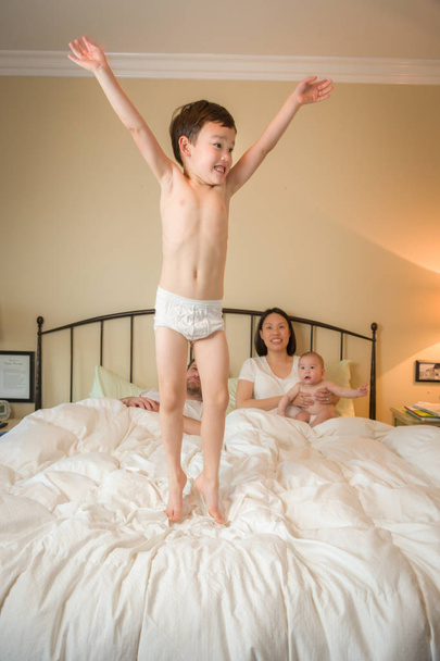 Mixed Race Chinese and Caucasian Boy Jumping In Bed with His Fam - Photo, Image