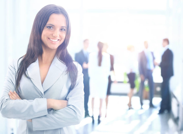 Успішна бізнес-леді стоїть зі своїм персоналом на задньому плані в офісі
 - Фото, зображення