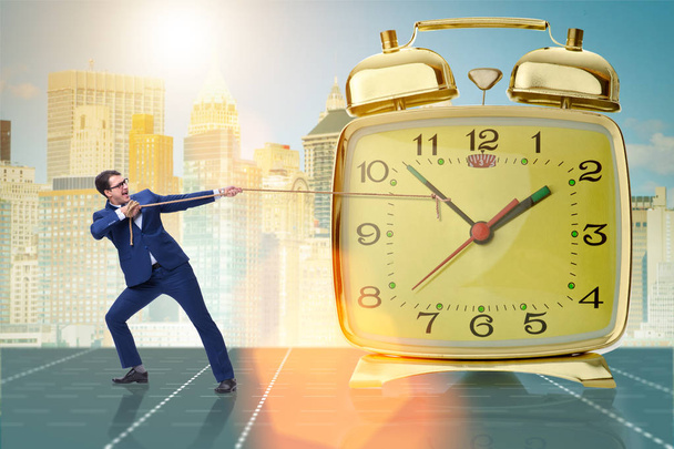 Biznesmen ciągnięcie zegar w czasie koncepcji zarządzania - Zdjęcie, obraz
