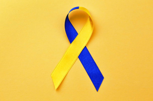 Blue-and-yellow ribbon on color background - Фото, изображение