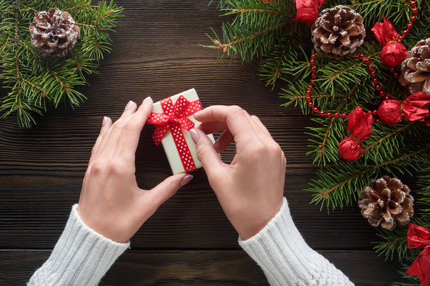 Beautiful female hands holding a Christmas present in box with red bow. - 写真・画像