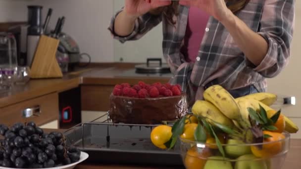 Brunette young woman making pictures of her chocolate and raspberry cake. Steadicam 4K video - Záběry, video