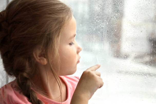  little girl looking out of window - Фото, изображение
