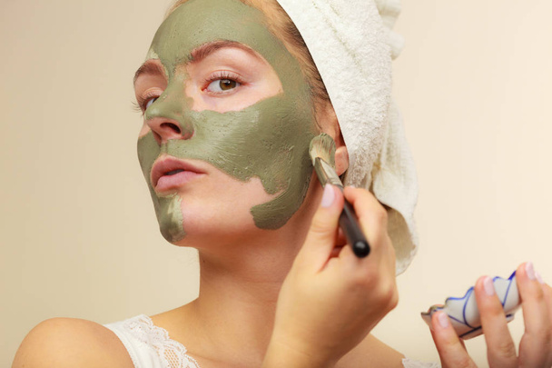 Woman applying with brush clay mud mask to her face  - Valokuva, kuva