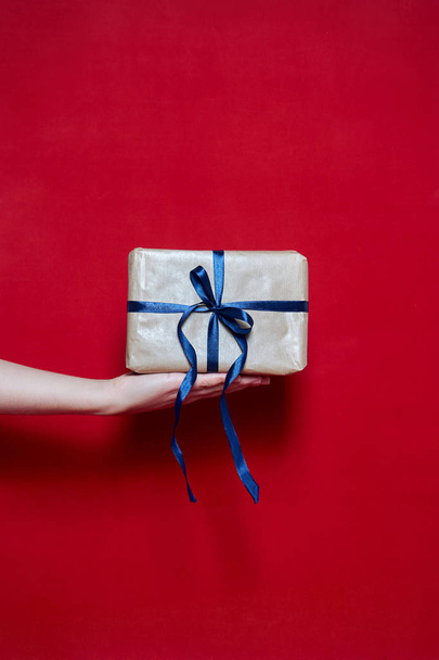 Womans Hand holding a box gift on red background - Foto, Imagem