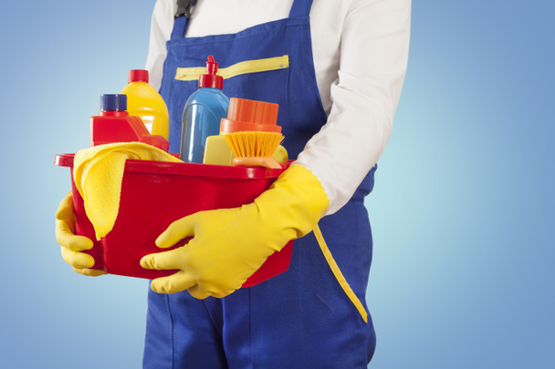 Uomo con prodotti per la pulizia su sfondo blu
 - Foto, immagini