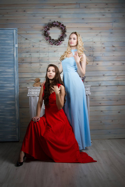 Dos chicas jóvenes en vestidos largos en una habitación con chimenea
 - Foto, Imagen