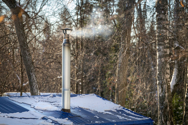 Pijp met rook in de winter bos - Foto, afbeelding
