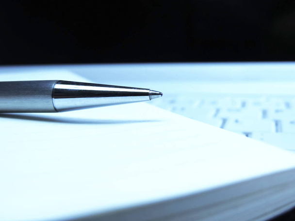Πένα και το χαρτί σε ένα λευκό φορητό πληκτρολόγιο - Φωτογραφία, εικόνα