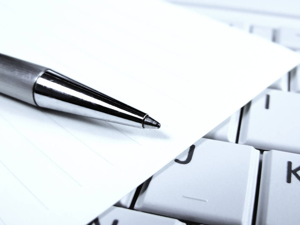 Ручка и бумага на белой клавиатуре ноутбука
 - Фото, изображение
