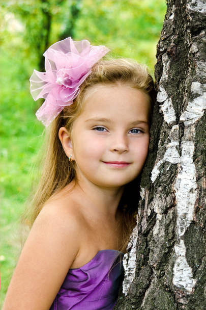 Portrait cute little girl standing near the tree - 写真・画像