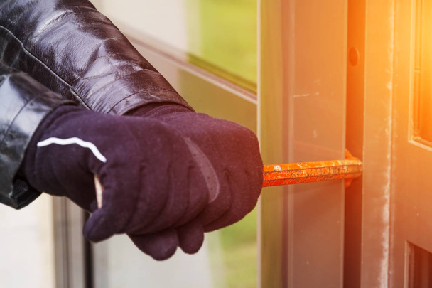 Burglar wearing leather coat breaking in a house - Valokuva, kuva