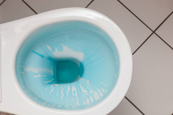 White toilet bowl with blue detergent - 写真・画像