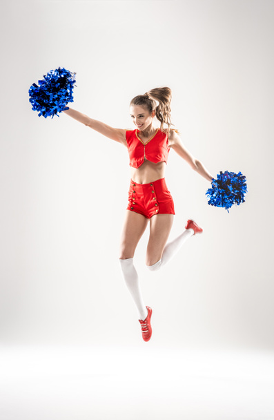 Cheerleader jumping with pom-poms - Photo, image
