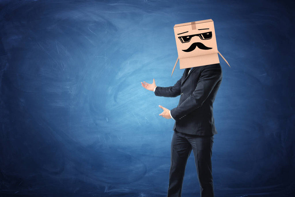 Businessman wearing cardboard box with drawn sun glasses and moustache on his head - Fotó, kép