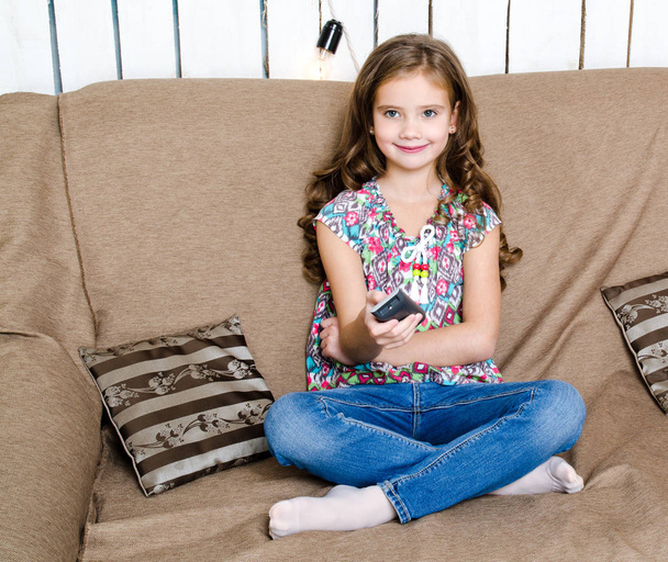 Cute little girl holding a remote control - Foto, afbeelding
