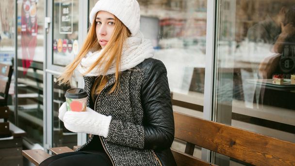 woman in white scarf and hat drinks coffee - Zdjęcie, obraz