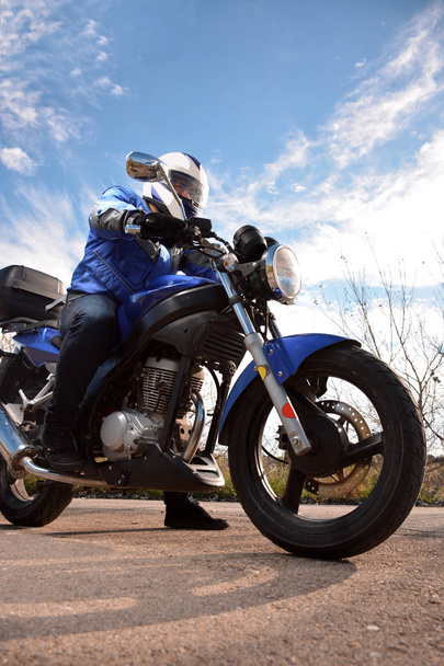 motociclista con casco blu passando da una strada
  - Foto, immagini