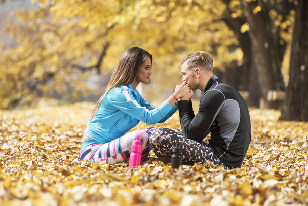 Krásná mladá dvojice odpočívá a líbání po úspěšném výcviku v parku. Podzimní prostředí. - Fotografie, Obrázek