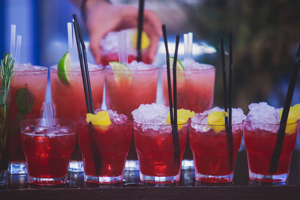 Beautiful row line of different colored alcohol cocktails on a party, martini, vodka,and others on decorated catering bouquet table on open air event, picture with beautiful bokeh - Фото, зображення