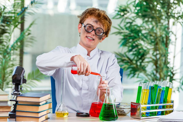 Νεαρός τρελός χημικός που δουλεύει στο εργαστήριο - Φωτογραφία, εικόνα