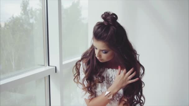 Όμορφη νεαρή γυναίκα μελαχρινή ποζάρουν κάθεται κοντά στο παράθυρο - Πλάνα, βίντεο