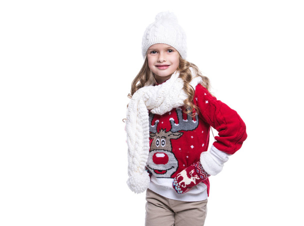 Cute smiling little girl with curly hairstyle wearing knitted sweater, scarf, hat and gloves isolated on white background. Winter clothes. - Foto, imagen