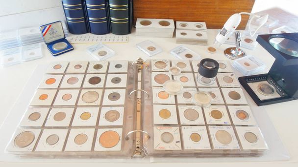 Round magnifying glass on album with coins from different countries - Numismatic scene - Photo, Image