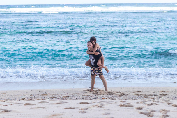 Young happy couple having fun on a tropical resorts white beach of Bali island, Indonesia. - Foto, Imagen