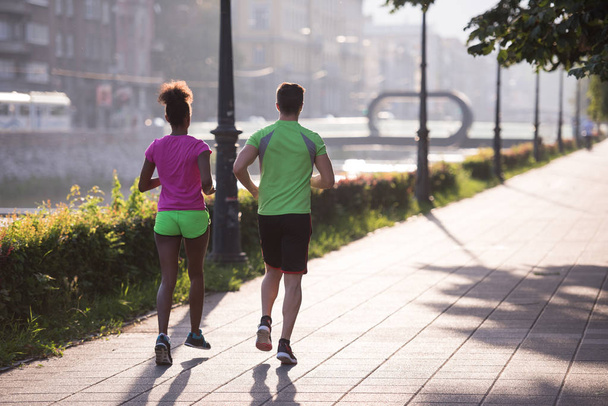 молода багатоетнічна пара біжить по місту
 - Фото, зображення