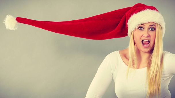Surprised girl wearing blowing santa claus hat - Fotó, kép