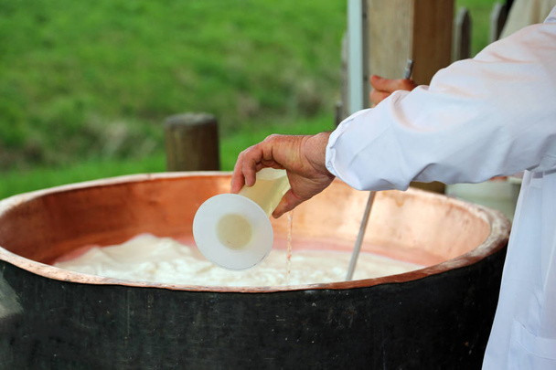 kaasproducent giet stremsel in de grote koperen ketel - Foto, afbeelding