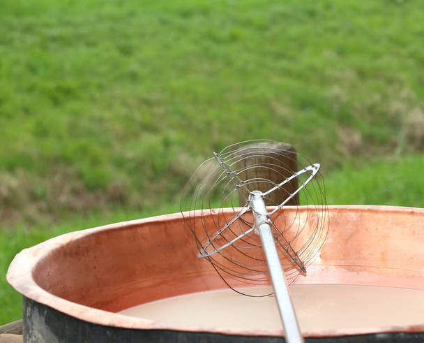 ferramenta para misturar o leite coalho no caldeirão de cobre para produzir
 - Foto, Imagem