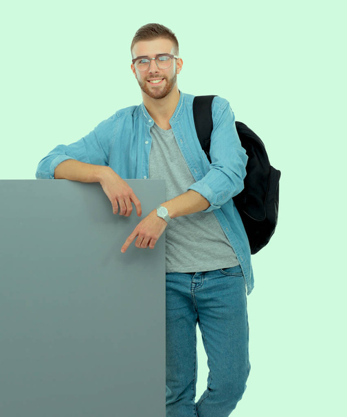 Portret van een lachende mannelijke student bedrijf leeg bord - Foto, afbeelding