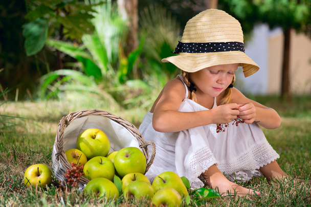 Fille assise sur l'herbe avec un panier de pommes
 - Photo, image