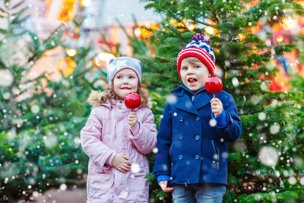 Zwei kleine Kinder essen Zuckerapfel auf dem Weihnachtsmarkt - Foto, Bild