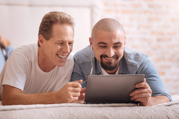 Amused two men watching videos together - Foto, imagen