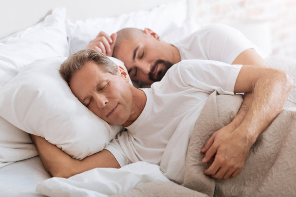 Positive delighted non-traditional couple sleeping together - 写真・画像