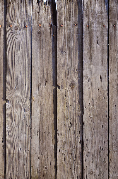 die Textur der verwitterten Holzwand. Alter Holzzaun aus vertikalen flachen Brettern - Foto, Bild