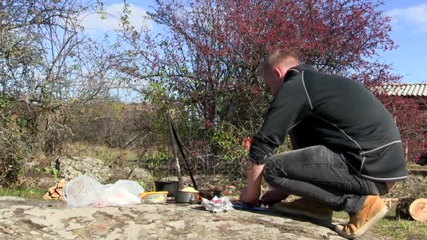 Cooking  food outdoors near bonfire. Man cuts meat - Footage, Video