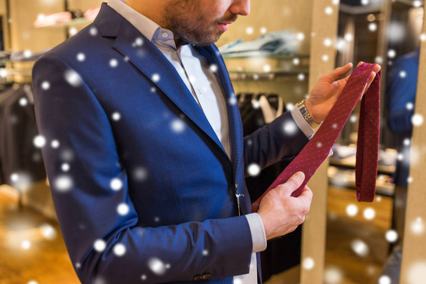 close up of man trying tie on at clothing store - 写真・画像