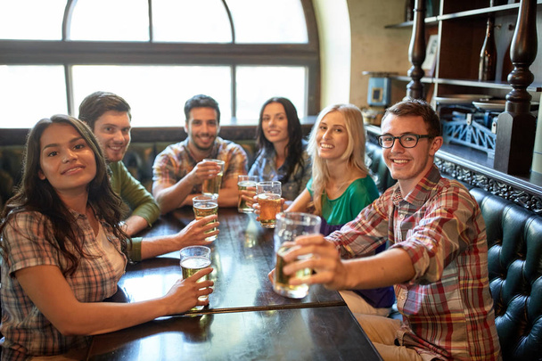 happy friends drinking beer at bar or pub - Photo, image