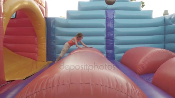 Zeitlupe: kleines hübsches Mädchen springt auf einem aufblasbaren Trampolin. - Filmmaterial, Video