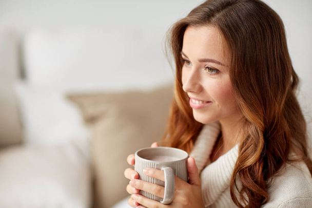 happy woman with cup of cocoa or coffee at home - Foto, afbeelding