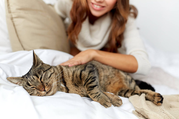 happy young woman with cat lying in bed at home - Foto, Imagem