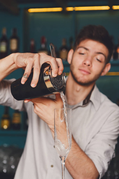 Joven barman guapo vertiendo bebida de cóctel en el vaso
 - Foto, Imagen
