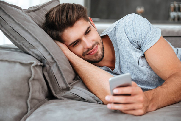 Young man chatting while lies on sofa - Foto, Imagen